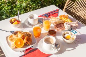 a white table with breakfast foods and drinks on it at Hôtel Bahia in Villeneuve-Loubet