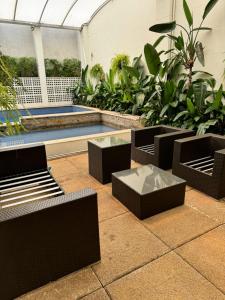 a room with chairs and a pool and plants at Studio no Coração do Jardins Moderno e Sofisticado in São Paulo