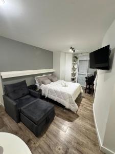 a bedroom with a bed and a chair and a television at Studio no Coração do Jardins Moderno e Sofisticado in São Paulo