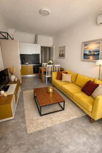 a living room with a yellow couch and a table at Shengjin apartaments kozmai in Shëngjin