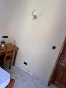 a room with a white wall with a lamp and a table at Safari Haven Villa in Moshi