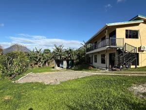 a house with a balcony and a grass yard at Arenal cautiva in El Castillo de La Fortuna