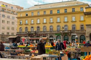 a market in front of a large yellow building at Apartments DOLAC Zagreb in Zagreb