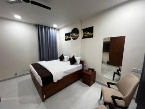 a bedroom with a bed and a chair and a mirror at Mayura palace in Jaipur