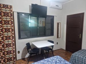 a room with a white table and chairs and a window at Flat Casa Grande in Itapira