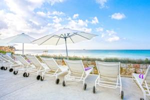 a beach area with chairs, tables and umbrellas at Hotel Be Live Adults Only Marivent in Palma de Mallorca