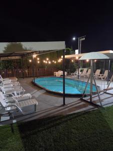 a swimming pool with chairs and an umbrella at night at Garni Hotel & Spa Nicolo in Kruševac