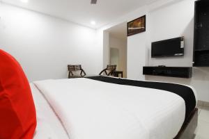 a bedroom with a white bed and a flat screen tv at Collection O Mythri Hotel Near By ECIL, AS RAO Nagar, Sainikpuri in Hyderabad +23 photos