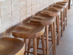 a row of wooden stools lined up against a wall at Ibis Valencia Alfafar in Alfafar
