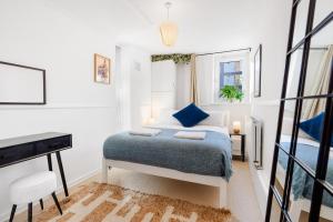 a white bedroom with a bed and a desk at Stylish 2 bed Central London in London