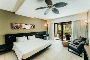 a bedroom with a bed and a chair and a ceiling fan at Crystals Beach Resort Belle Mare, a member of Radisson Individuals in Belle Mare +133 photos