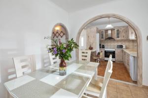 a kitchen and dining room with a glass table with flowers at Villa Anastasis in Halikounas +23 photos