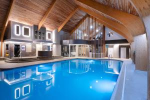 a large swimming pool in a building with wooden ceilings at Park Farm Hotel in Norwich