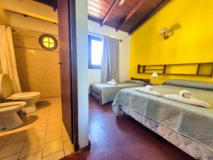 two beds in a room with a toilet and a bathroom at Hotel Spileon in Villa Gesell