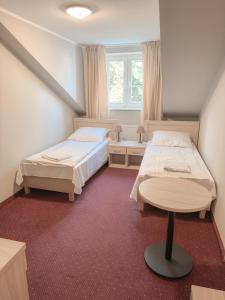 a bedroom with two beds and a table at Złote Runo - Kameralny hotelik & Restauracja in Karolina