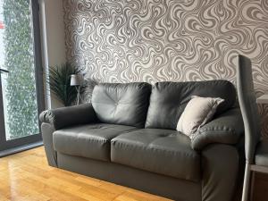 a leather couch in a living room with a wall at 2 Bedroom Apartment - Henry St Central Liverpool in Liverpool +19 photos