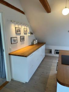 a kitchen with white cabinets and a wooden counter top at Havnehuset Kerteminde in Kerteminde +16 photos