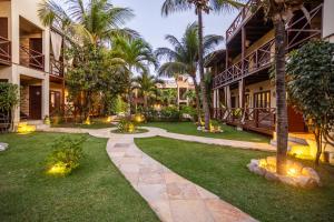 a courtyard of a hotel with palm trees and a walkway at Apartamento Breezes in Jericoacoara