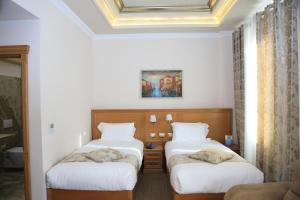 two twin beds in a room with white walls at HOTEL BOCA Center in Tirana +73 photos