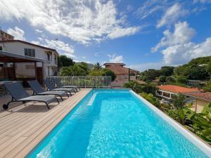 a swimming pool with chairs on a wooden deck at Villa Altaïa - Sea View & Infinity Pool in Les Trois-Îlets