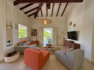a living room with two couches and a tv at Villa Altaïa - Sea View & Infinity Pool in Les Trois-Îlets