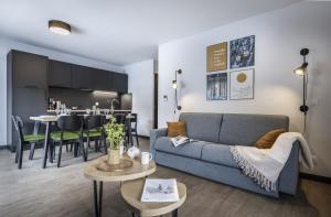 a living room with a couch and a dining room at Résidence Club MMV SERRE CHEVALIER Le Serra Neva in La Salle-les-Alpes