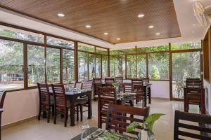 a restaurant with tables and chairs and windows at Misty Lake Resorts Munnar By Sylora Hotels in Munnar