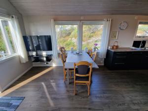 a dining room with a table and chairs and windows at Færøya 49 in Nekkøyane