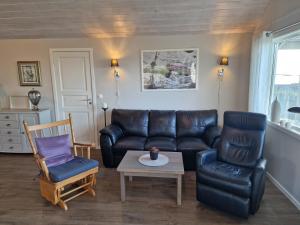 a living room with a leather couch and two chairs at Færøya 49 in Nekkøyane