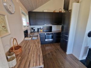 a kitchen with a black refrigerator and wooden floors at Færøya 49 in Nekkøyane +10 photos