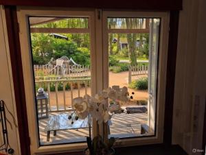 an open glass door with a view of a playground at Chalet Bosrust met serre & privéparking Natuur nabij Maastricht in Lanaken