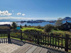 a wooden bench next to a fence with a view of the water at Færøya 49 in Nekkøyane