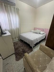 a bedroom with a bed and a couch in it at Casa Centro de Caraguatatuba in Caraguatatuba