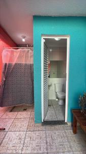 a bathroom with a toilet and a blue wall at Casa Centro de Caraguatatuba in Caraguatatuba +9 photos