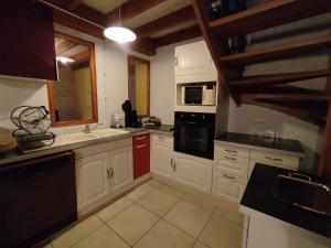a kitchen with white cabinets and black appliances at Gîte de la Forêt in Saint-Jeanvrin