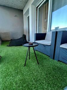 a room with a table and a couch and green carpet at Chambre privée chez habitant à Sète in Sète