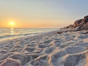 a sandy beach with the sun setting over the ocean at Da Luca in Càbras