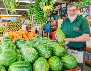 a man standing in a store holding a bunch of watermelons at La casita tropical in Florida City