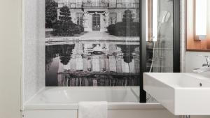 a bathroom with a bath tub and a sink at Campanile NATURE - Compiegne in Compiègne +21 photos