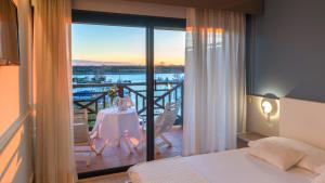 a bedroom with a table and a balcony with a view at Hotel Marina Uno in Lignano Sabbiadoro