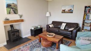 a living room with a leather couch and a fireplace at West Gallaton Farmhouse in Stonehaven +18 photos