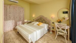 a bedroom with a bed and a mirror and a chair at Hotel Marina Uno in Lignano Sabbiadoro