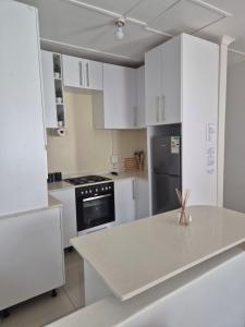 a kitchen with white cabinets and a white counter top at Charming Cottage for Getaways in Empangeni