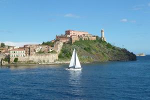 a sail boat in the water with a castle in the background at La Mansarda degli Ulivi in Portoferraio