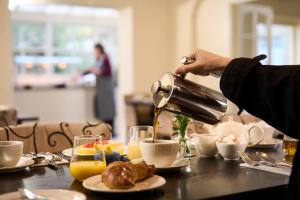 a person pouring coffee into a cup on a table at Plockton Inn, by Highland Coast Hotels in Plockton +52 photos