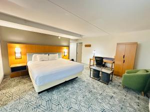 a hotel room with a bed and a green chair at Ashbourne Hotel Canton Hall of Fame I-77 in Canton +75 photos
