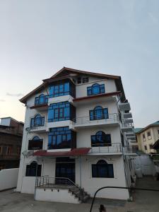 a tall white building with blue windows at Hotel Sada Bahar in Srinagar +17 photos