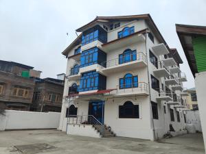 a tall white building with blue windows at Hotel Sada Bahar in Srinagar