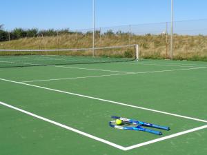 una raqueta de tenis y una pelota en una pista de tenis en Le Cap Hornu en Saint-Valery-sur-Somme