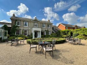 a group of tables and chairs in front of a house at Park Farm Hotel in Norwich